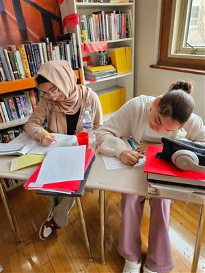 Photo of two female students at desks, at work analyzing texts.